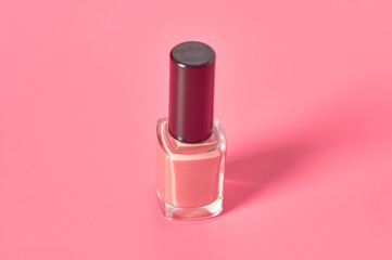 Full bottle of luxury nail polish on pink background. Beauty and fashion concept