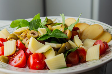 Prato com salada com tomatinhos folhas de manjericão e queijos. 