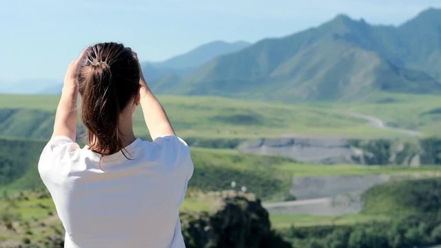 Back view of a girl photographing a beautiful landscape on a smartphone. Cinematic and inspiring travel blogger lives a motivational adventure. Happy young woman in mountains