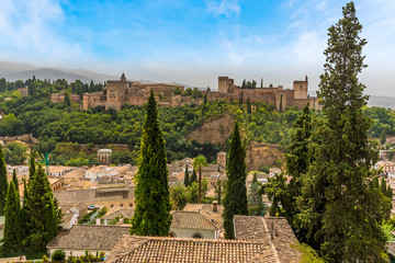 Fototapeta na wymiar A view over the rooftops of the Albaicin district of Granada towards the Alhambra Palace and the Sierra Nevada mountains in the summertime