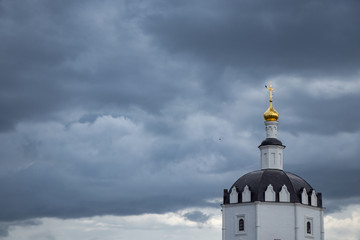 black and white church with golden dome against storm clouds