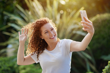 Portrait of a pretty redhead woman using a mobile phone and taking a selfie
