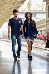 Happy young Asian tourist couple travelling together at the railway station
