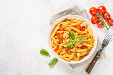 Pasta with chicken and vegetables at white table.