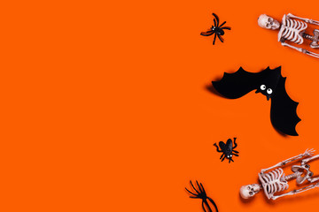 Halloween decoration picture - orange background with spider, bat, skeletons. Flat lay with a place for your text.