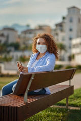 A beautiful young woman in the mask using a smartphone