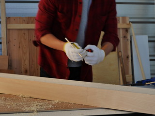young man Asian carpenter with red shirt  in workshop store working on wood plank and measurement...