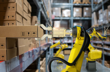 yellow robotic arm carry cardboard box in warehouse
 - obrazy, fototapety, plakaty