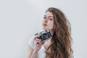 Curly girl takes pictures on an old film camera. Holds a camera in his hand. Photographer services