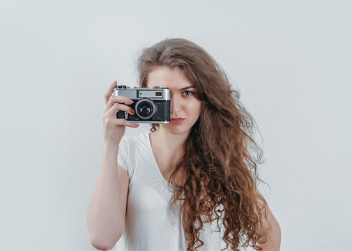 Curly girl takes pictures on an old film camera. Holds a camera in his hand