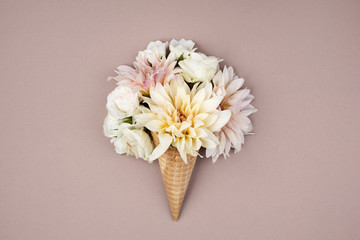 Waffle horn with fresh white flowers on a pastel lavender background. Fall flowers in an ice cream cone. Minimalist autumn concept . 