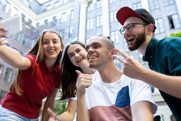Taking selfie. Group of friends taking a stroll on city's street in summer day. Handicapped man with his friends having fun. Inclusion and diversity concept, normal lifestyle of special groups of