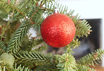 Obraz na płótnie Canvas Close up view of red christmas ball hanging on tree with green background. Christmas holiday, New Year 2021.