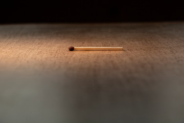 One whole match is lying on the wooden table