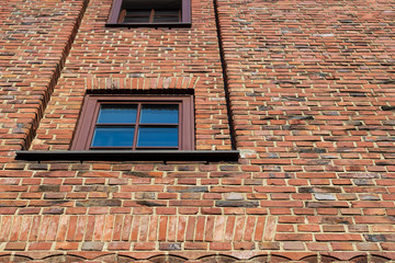 A brick wall from below with two windows on the left side. Lines are following a nice pattern to the top of the image.