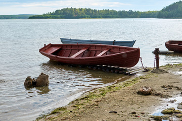 Obraz premium Old wooden boats lie on the shore of the lake. Rain on the lake.