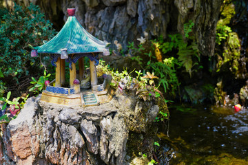 a small figure of a pagoda on a cleft near a stream