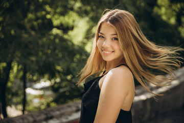 A teenage girl is having a walk in a green city park