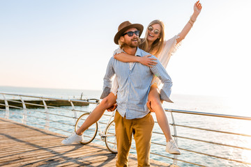 attractive happy couple laughing traveling in summer by sea, man and woman wearing sunglasses, boho...
