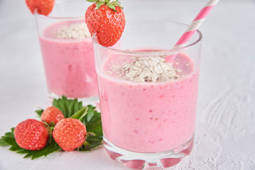 Strawberry milk shake in glass with straw and fresh berries on a white background