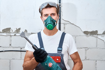 Renovation concept. Man in builder uniform with hammer drill make repairs in the room