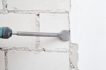 Man with demolition hammer remove stucco from wall. Renovation concept