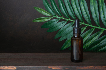 Bottle of peach oil, decorated with peaches on brown background.