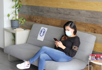 Latin woman with protective face masks sitting in waiting room with social distance, new normal...
