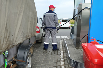 Fototapeta na wymiar gas station worker refueling a car with a trailer