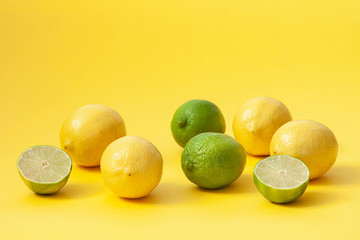 Lemons and limes on a yellow background. Food concept