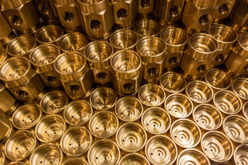 Shiny yellow metal parts background. Shiny brass metal threaded hexagonal parts after turning and...