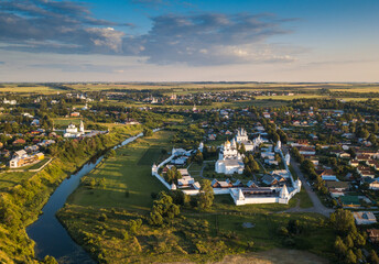 Panoramic aerial view of ancient city Suzdal and Intercession Pokrovsky Monastery in sunset.The Golden Ring of Russia. Vladimir region. Aerial drone photo.