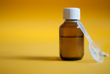 Cough syrup. Cold medicine. Pills and medicine on a yellow background. Pharmaceutical preparations for cough, flu.