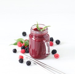 Smoothie of fresh raspberries and blackberries in a jar with a bamboo straw on a light background copy space 