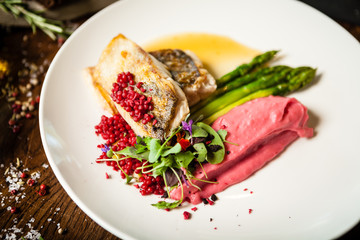 Pike-perch fillet. Asparagus, pearl couscous, white wine sauce, beet-flavored mashed potatoes. Delicious seafood fish closeup served on a table for lunch in modern cuisine gourmet restaurant