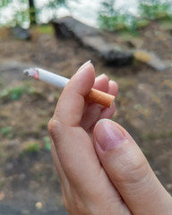 Burning cigarette in a woman's hand close-up. Concept of smoking harm.