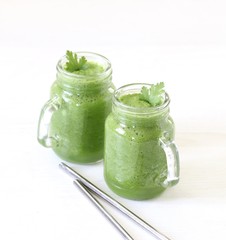 Green smoothie with parsley and spinach with a bamboo straw on a light background