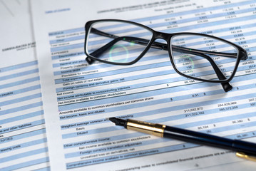 Balance sheet in stockholder report book with glasses and pen, balance sheet is mock-up