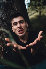 The young man leaning on a tree in the forest asks why, nature and people concept