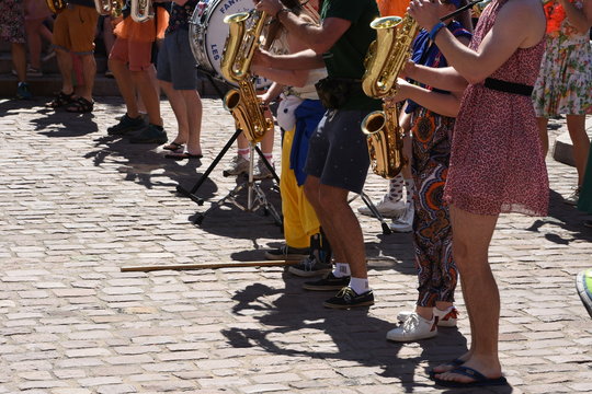 Street musicians with wind instruments and drums in color clothing in town of Colmar, France during weekend sunny summer day to cheer up tourists.
