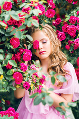Obraz na płótnie Canvas beautiful girl on a background of pink roses. Young model in a blooming garden