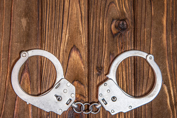 Handcuffs shackles on a wooden background