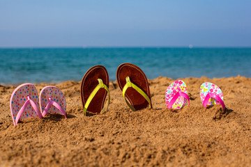 Slippers on the beach are standing in the sand.