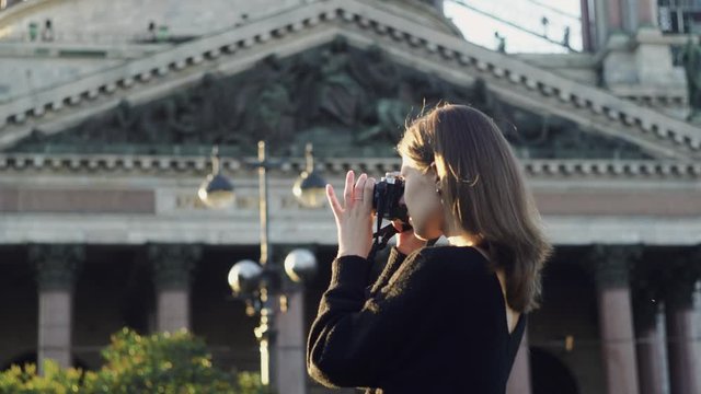 Young beautiful woman taking photos on background of temple. Media. Woman takes photos with professional camera on background of temple. Romantic rays of sun falling on woman photographer