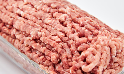 Fresh minced meat close-up in a glass dish plate. Isolated on a white background.