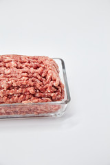 Fresh minced meat close-up in a glass dish plate. Isolated on a white background. Vertical photo