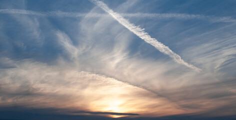 Gray, white and orange clouds in the blue sky at dawn