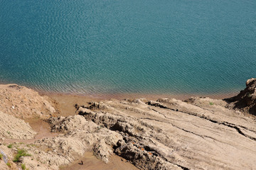 Rocky sandy relief sea shore. Azure water.