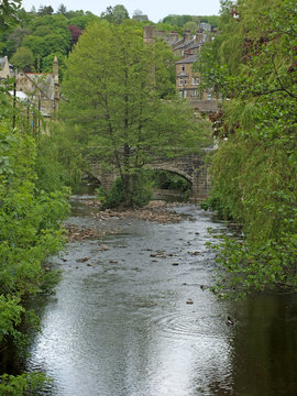 view of the town of hebden bridge with the river and bridge surrounded by summer trees