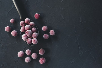 Frozen fresh farm cherries in plastic spoon on black background. Close-up. Top view